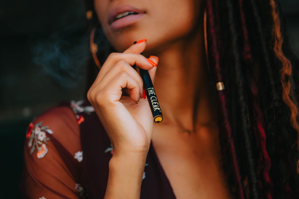 Woman holding a CBD disposable vape bar in her hand while exhaling vapour