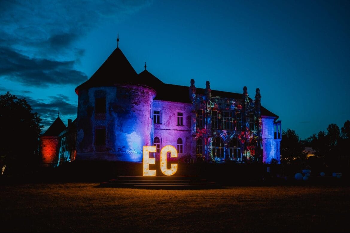 Electric Castle building at night with sign in front