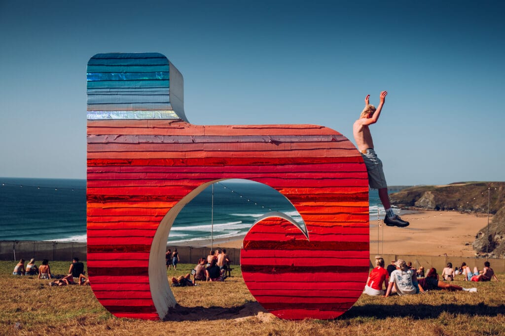 Boardmasters sign with person jumping off and beach in background