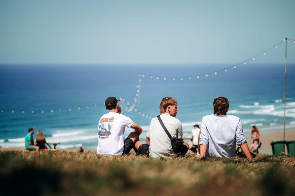 Boardmasters people sat on grass looking at beach