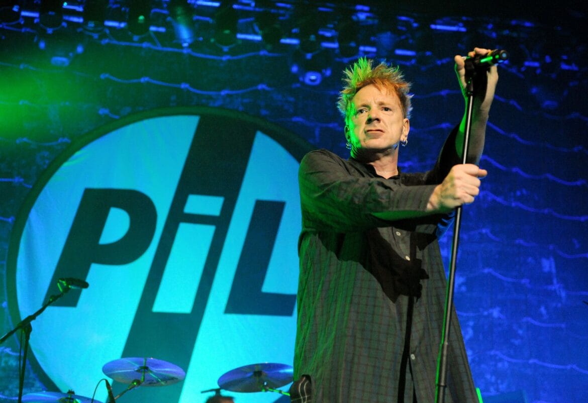 John Lydon on stage with Public Image Ltd logo in the background